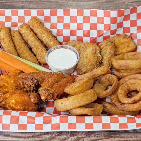 A red and white checkered basket filled with mozzarella sticks, chicken wings, onion rings, and dipping sauce.